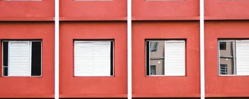 Close-up side-view of a red building showing 4 windows