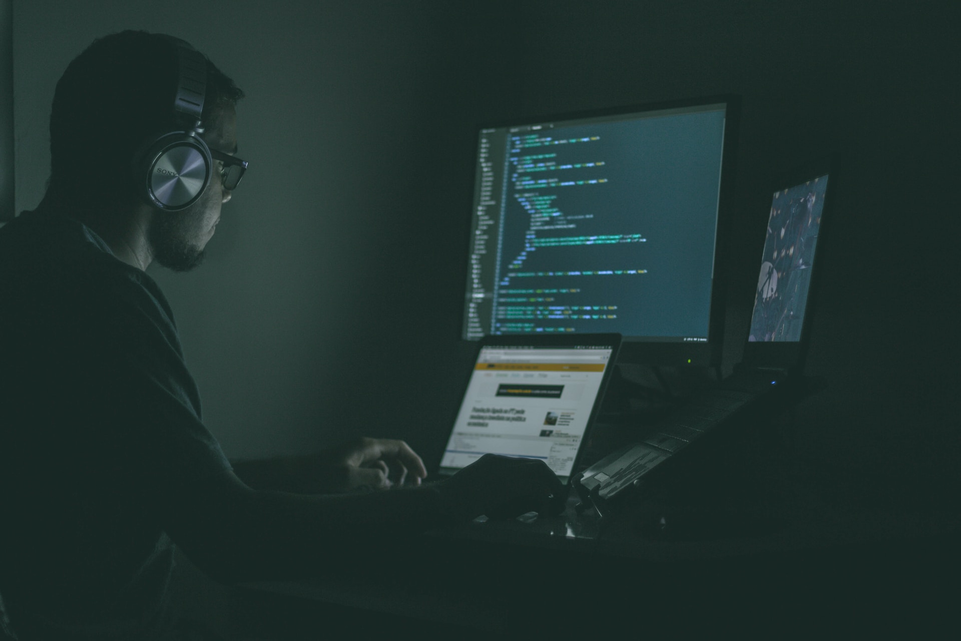 User looking at code on a computer in a dark room