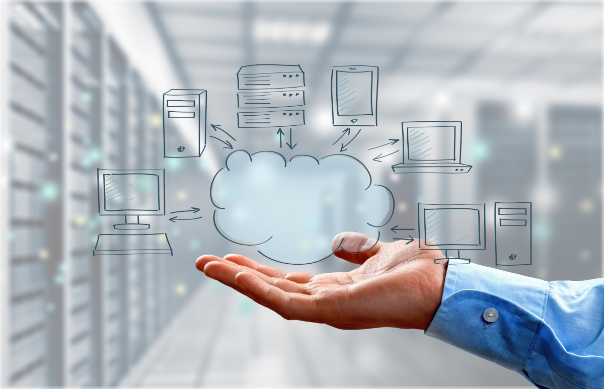 A hand holding up a 2D cloud that is connected to server, desktop, and laptop icons, in front of a server room backdrop
