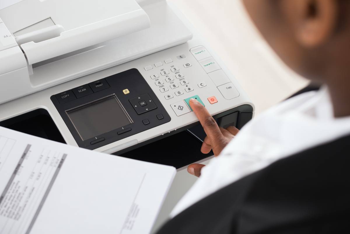 A business woman pressing a green 'Print' button on a white printer