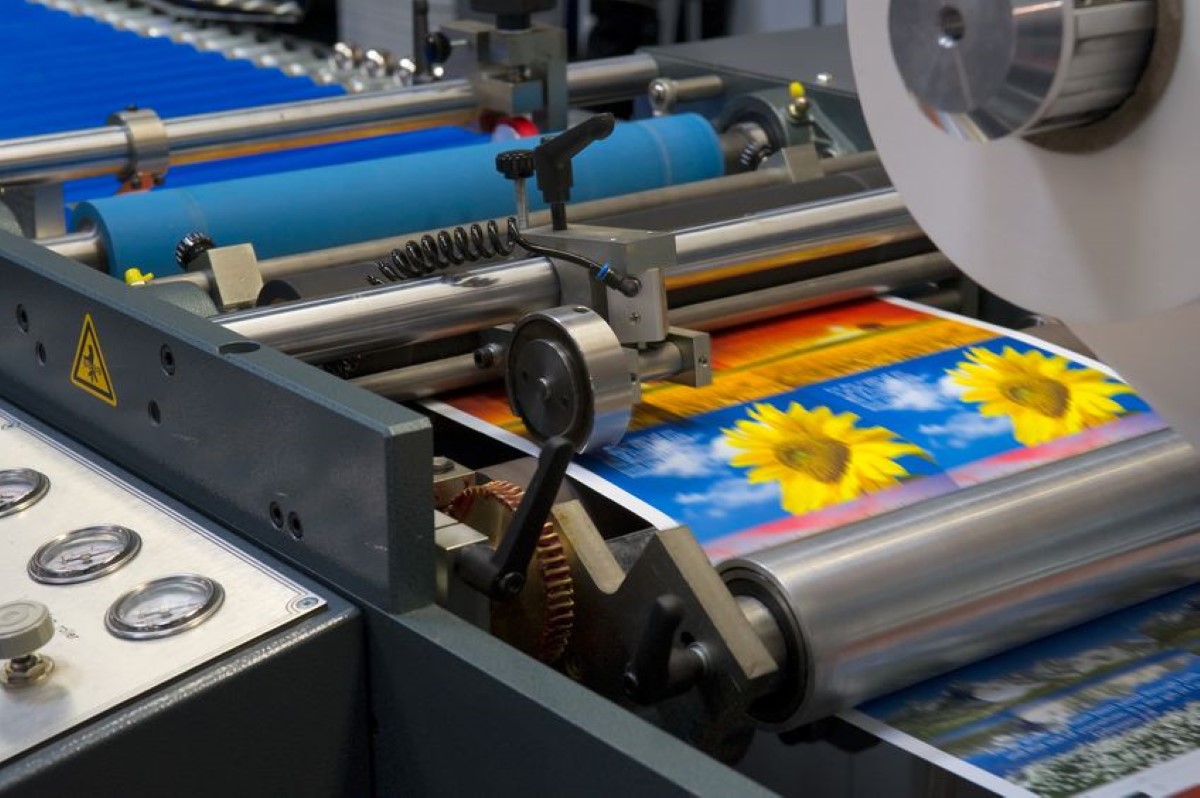 A production print machine processing images of sunflowers.