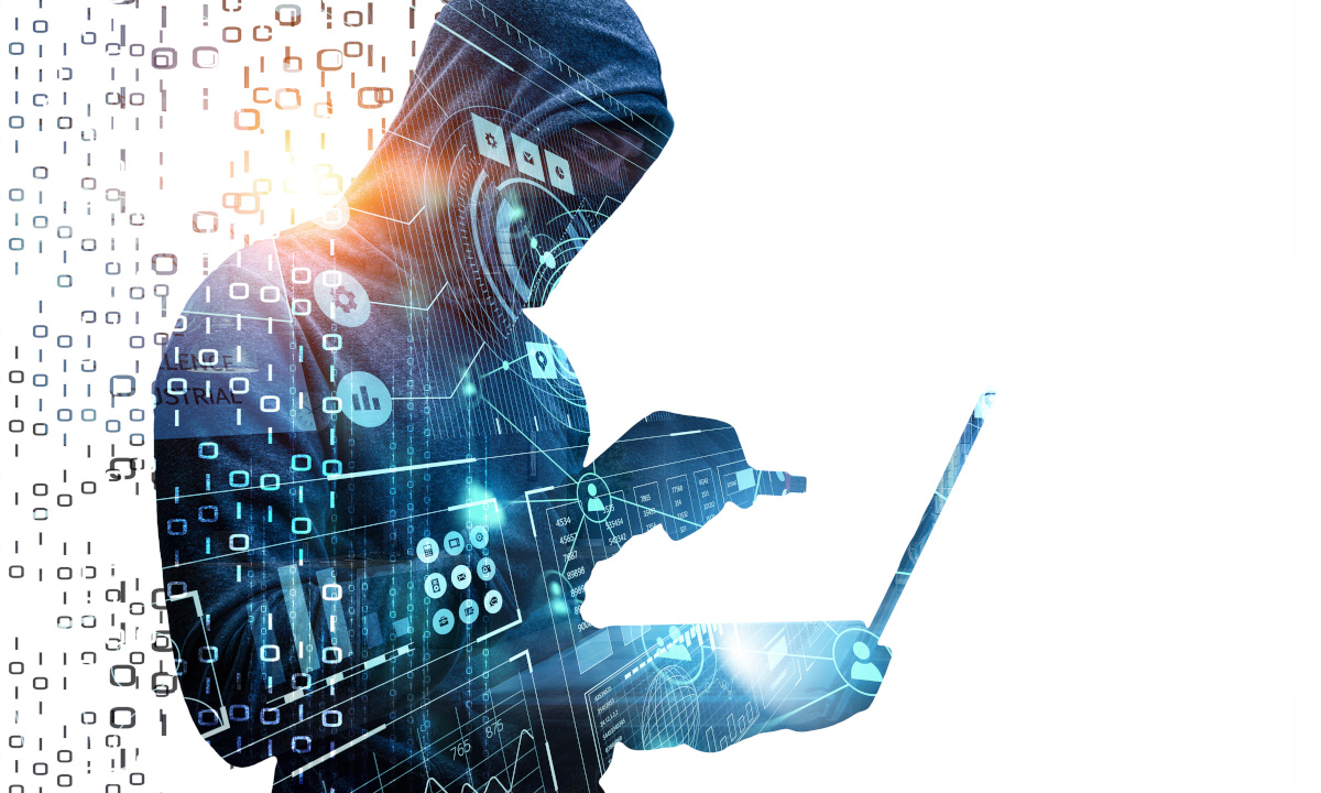 A hooded figure wearing a face-covering holding a USB threateningly up to a laptop with binary and other icons relating to technology interposed over the image to represent cyber security and malware threats
