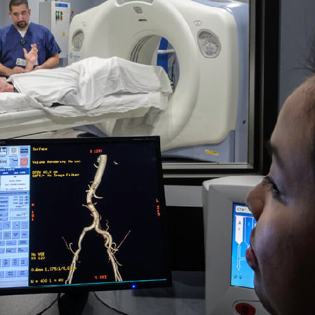 Technician reading a diagnostic screen, backdrop of a patient in a scanning machine