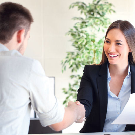 Businesswoman shaking the hand of a man sitting across the table from her