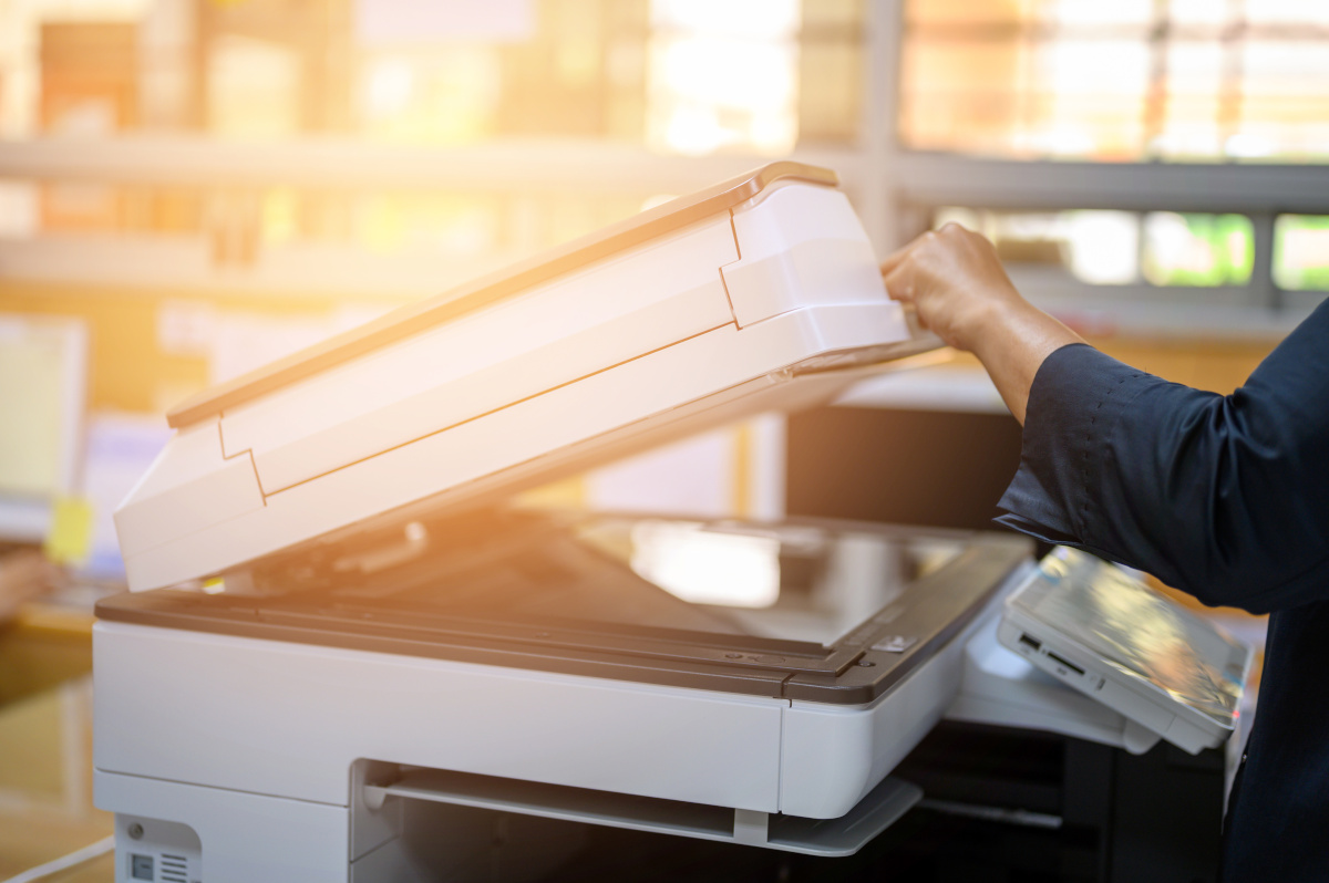 Close up of a copier/printer having its top opened with the sun setting in the background